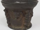un vieux vase en bronze orné d'un motif représentant un visage