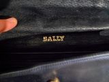 une personne tenant un sac à main noir sur lequel figure un nom