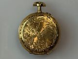 a gold pocket watch with a picture of a woman on it