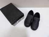 pair of black shoes sitting next to a box on a white surface