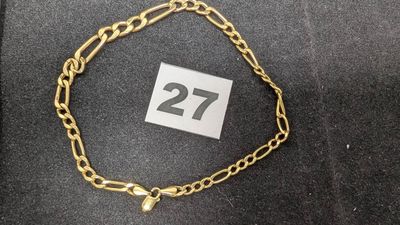 un gros plan d'un bracelet à chaîne en or sur lequel figure le chiffre 27