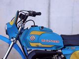 a blue and yellow dirt bike parked in front of a wall