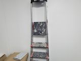 a ladder that is leaning against a wall next to a pile of boxes