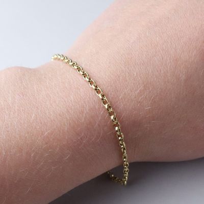 a close up of a person ' s arm with a gold chain bracelet