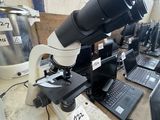 a microscope that is sitting on a table with laptops