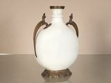 a white vase sitting on a table with a gold handle