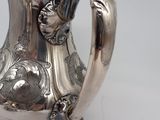 a silver tea pot with a handle on a table