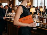 a woman standing at a bar holding a glass of wine
