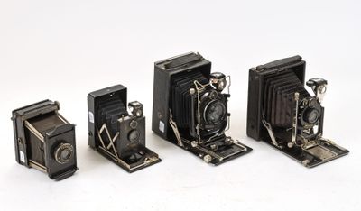 quatre appareils photo anciens sont alignés sur une surface blanche