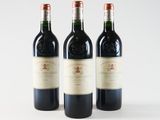 three bottles of red wine are lined up on a white surface