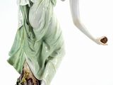 an antique figurine of a woman in a green dress holding a flower