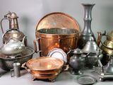 de nombreux objets en argent et en cuivre de toutes sortes posés sur la table