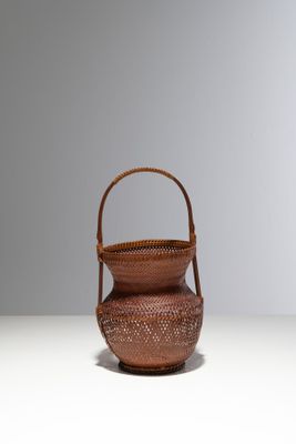 petit panier tressé muni d'une anse, posé sur un fond blanc