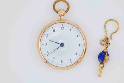 a gold pocket watch with a blue bead key hanging from it