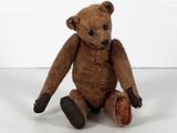 un ours en peluche marron assis par terre