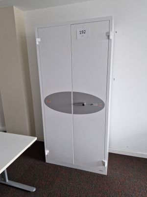 a white cabinet in the corner of a room next to a white table