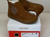 des chaussons pour bébé marron à pois, ornés de paillettes, posés sur une boîte