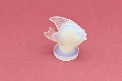 a plastic fish that is sitting on a pink surface