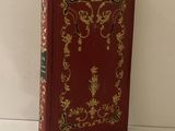 un livre rouge orné de motifs dorés, posé sur une table