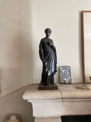 une statue représentant une femme debout sur une cheminée