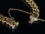 two pieces of gold jewelry on a black surface with a black background