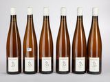 six bouteilles de vin sont alignées sur une table