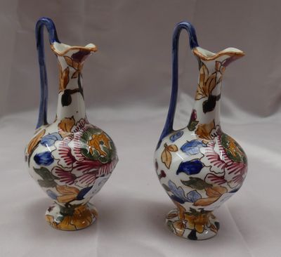 Deux vases ornés de motifs floraux sont posés sur une surface blanche.