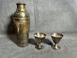 deux vases en argent et une coupe en argent posés sur un tissu gris