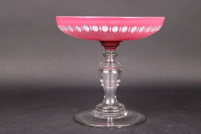 a pink glass bowl on a glass stand on a black surface