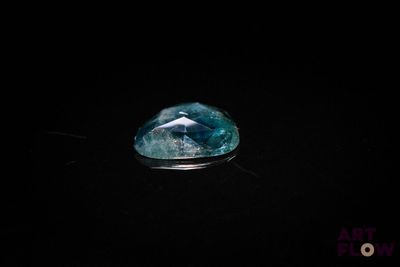 a close up of a blue and white diamond on a black surface