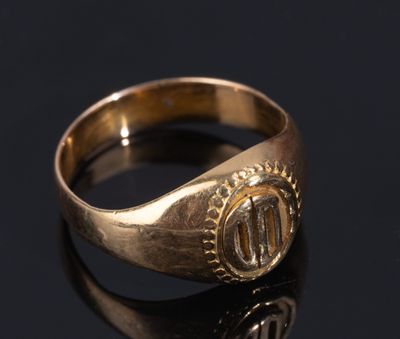 a close up of a gold signet ring on a black surface