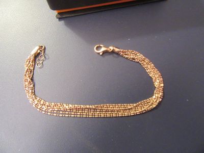 un bracelet en chaîne d'or posé sur une table, à côté d'un portefeuille