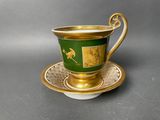 a green and gold cup and saucer on a saucer