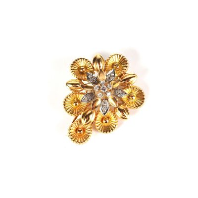un gros plan d'une broche en forme de fleur en or, ornée d'un diamant au centre
