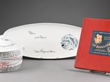 a red book sitting next to a white plate and a red book