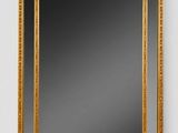 a gold framed mirror on a white wall with a black background