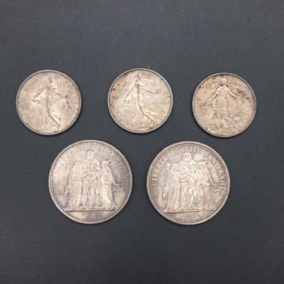 four different types of silver coins on a black surface