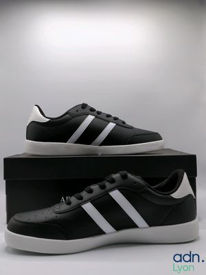 une paire de baskets noires et blanches posée sur une boîte
