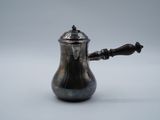 une cafetière ancienne en argent avec une poignée en bois sur fond blanc