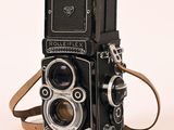 a black camera with a brown strap on a white background
