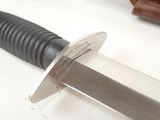 a close up of a knife on a table with a knife in the background