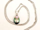 une chaîne en argent avec un pendentif en perle noire, sur fond blanc