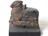 statue d'une vache coiffée d'un chapeau, assise sur un bloc de bois