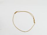 un bracelet en chaîne dorée orné d'un nœud sur un fond blanc