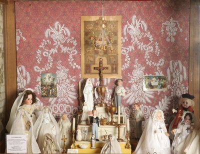 de nombreuses figurines dans une vitrine, avec un tableau accroché au mur