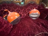 pair of orange lamps sitting on a red couch in a living room