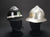 pair of firemen ' s helmets on mannequin heads against a black background