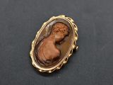 une image représentant une broche à l'effigie d'une femme, dans un cadre en or