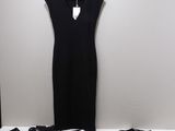 La robe noire se trouve à côté d'un pantalon noir et d'une paire de chaussures noires