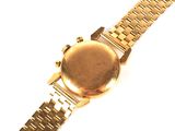 a gold watch on a gold bracelet on a white surface